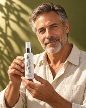 Load image into Gallery viewer, Man in his fifties with salt-and-pepper hair holding a Bio Follicle Normal Hair Loss Prevention spray
